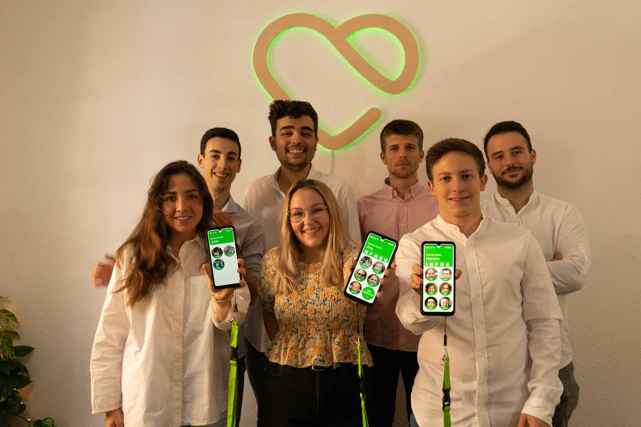 Imagen: los jóvenes que forman el equipo de la empresa posan delante del logo iluminado de la empresa sujetando varios dispositivos móviles.